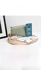 Detail view of sage green and beige crossbody bag with embroidered wide strap and phone