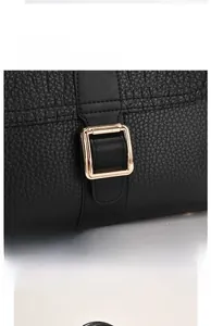 Detail of gold hardware buckle and black crocodile texture on leather handbag