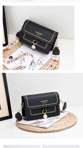 Detail view of black flap crossbody bag with U-shaped stitching and embroidered shoulder strap