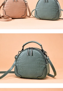 Detail of crocodile pattern texture on semi-circular shoulder bags with double zippers