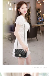 Detail of black quilted crossbody bag with crocodile texture and metal turn-lock
