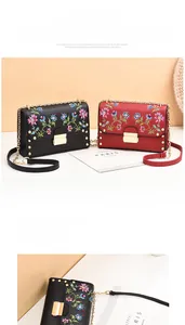 Detailed view of colorful floral embroidery and gold studs on PU leather crossbody bags