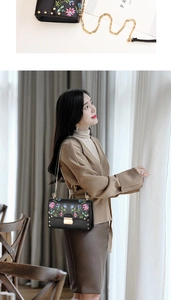 Detail of black PU crossbody bag with colorful floral embroidery and gold chain strap