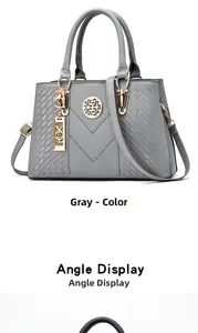 Detail of grey pebbled leather handbag with V-shaped stitching and golden metal hardware