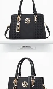 Detail view of black lychee grain leather handbag with gold metal logo and strap