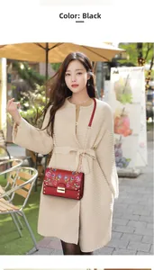 Detail of red PU leather handbag featuring colorful floral embroidery and metal chain strap
