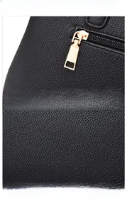 Detail of black lychee grain leather handbag with golden metal zipper and hardware