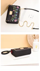 Detailed macro of black PU leather handbag featuring floral embroidery and golden rivets