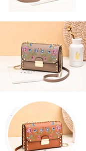 Detail of elegant PU leather crossbody bag featuring floral embroidery and gold rivets