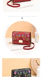 Detail of colorful floral embroidery on red and black PU leather crossbody bag with rivets