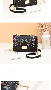 Close-up of black PU leather handbag with floral embroidery and golden metal hardware
