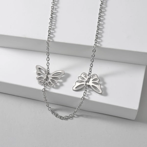 Minimalist silver butterfly pendant necklace on white geometric display stand
