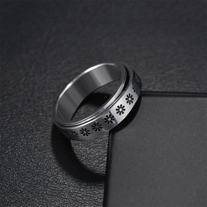 Macro shot of silver stainless steel spinner ring with engraved daisy floral patterns
