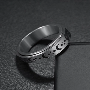 Detailed macro view of celestial spinner ring with moon and star engravings on black leather