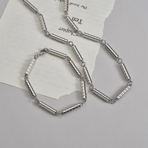 Details von Halskette und Armband aus Titanstahl im Bambus-Stil auf modernem Papierhintergrund