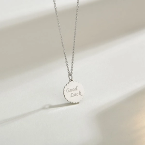 Minimalist round coin pendant necklace with Good Luck engraving and wavy edge design