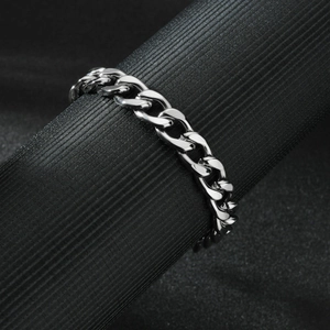 Polished silver stainless steel Cuban link bracelet for men and women on a black stand
