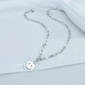 Détail d'un collier trombone en acier inoxydable argenté avec pendentif smiley ajouré