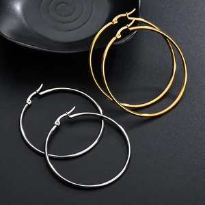 Polished gold and silver stainless steel hoop earrings set on a dark textured background