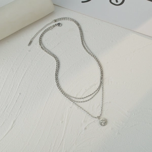 Three-layer silver beaded necklace with angel relief pendant on a minimalist background