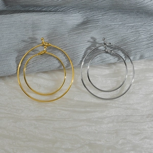 Close-up of polished gold and silver hoop earrings on elegant silk background fabric