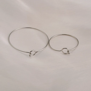 Minimalist titanium steel coil bracelets in silver finish on soft silk background