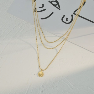 Triple-layered gold beaded necklace featuring a vintage angel relief coin pendant