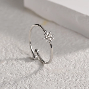 Bague étoile argentée ajustable avec zircons vue à 45 degrés sur un fond blanc texturé