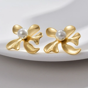 Detail of matte gold abstract floral earrings featuring a central white pearl inlay