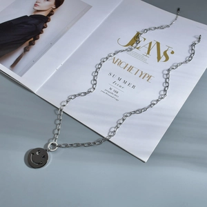 Détail du collier argenté avec pendentif visage souriant et yeux en forme d'étoile