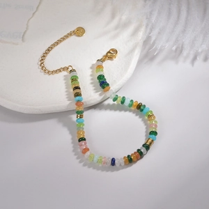 Détail d'un bracelet de perles colorées avec fermoir et plaque en acier doré