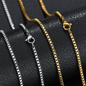 Détail de colliers chaîne box en argent et or avec fermoir mousqueton sur cuir noir