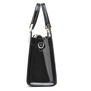 Side view of black patent leather handbag with glossy finish and gold D-ring hardware