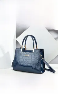 Detailed view of navy blue crocodile texture handbag with golden hardware and logo plate