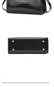 Detail view of black crocodile texture handbag showing bottom with gold protective studs