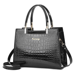 Detail of black faux crocodile patent leather handbag with dual handles and metal logo