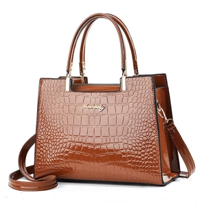 Detail shot of brown crocodile embossed texture on a high-gloss luxury handbag
