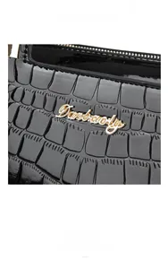 Close-up of black crocodile pattern leather texture with gold Danbaoly metal logo