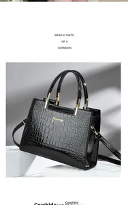 Detail of black crocodile pattern cowhide handbag with metallic logo and dual handles