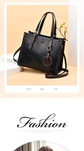 Detalle del bolso tote de cuero negro con costuras blancas y colgante redondo