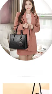 Detalle del bolso de hombro grande en cuero negro con textura de lichi y colgante redondo