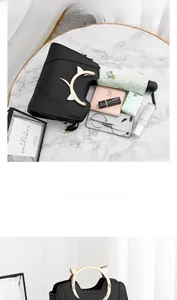 Détail du sac à main noir avec poignées dorées en forme de chat et intérieur spacieux