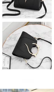 Détail du sac bandoulière noir avec poignée ronde dorée et oreilles de chat