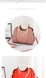 Détail des poignées dorées en forme de chat sur sacs à main en cuir rouge et rose