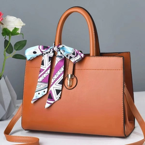 Brown leather handbag with gold twist lock and elegant patterned silk scarf on handle