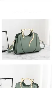 Détail du sac à main vert avec poignée métallique unique en forme de chat doré