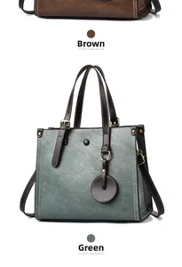 Detalle del bolso de hombro en cuero sintético texturizado con herrajes dorados y dije