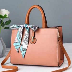 Pink faux leather tote bag with brown handles and a blue patterned silk scarf accessory