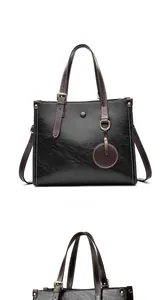 Primer plano de bolso tote de cuero encerado negro con correas marrones y herrajes oro