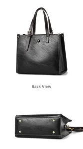Detalle de bolso tote negro con costuras blancas en contraste y pies metálicos dorados